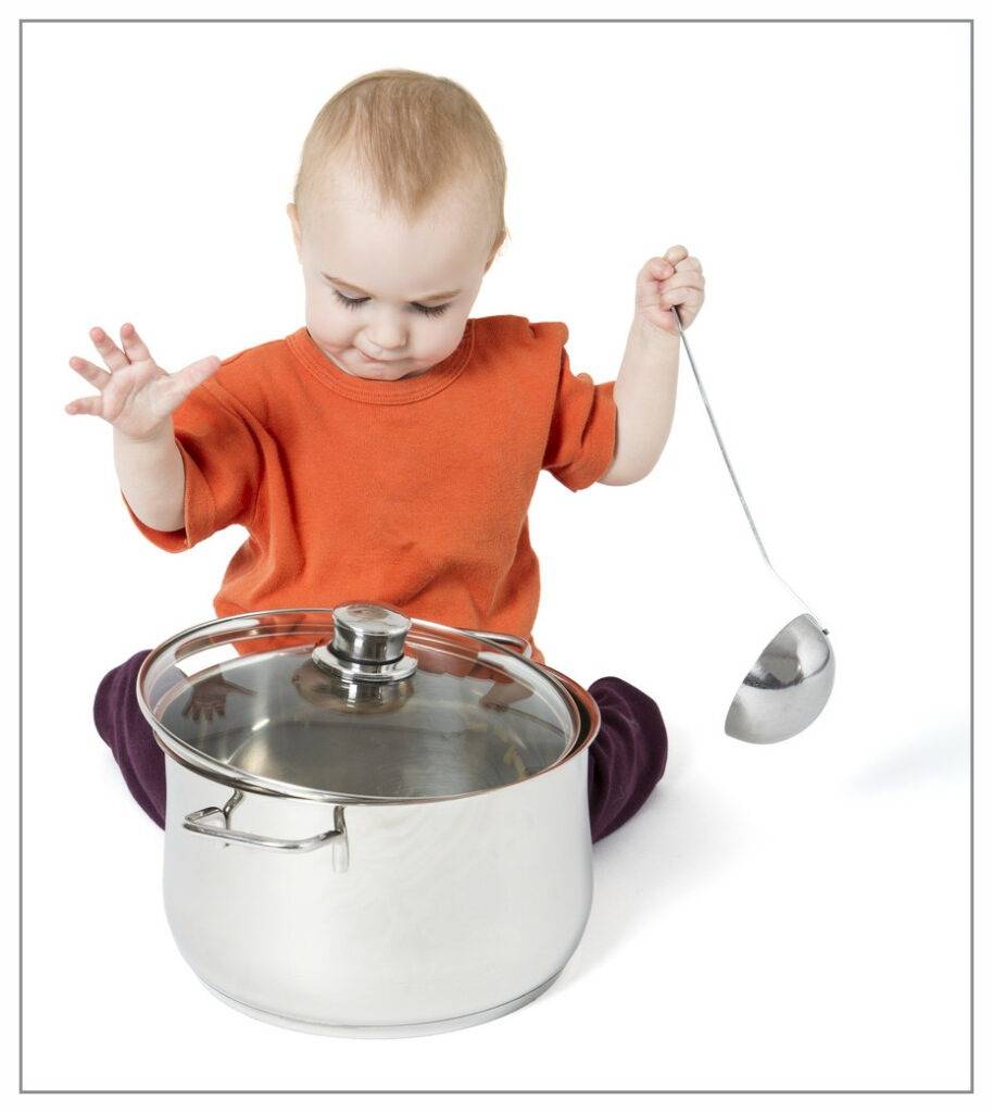Toddler playing with cooking pot and ladle