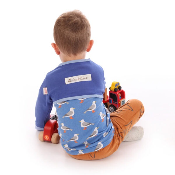 Back view of little boy sat on floor playing with toys, wearing t-shirt, trousers and children's bolero style night sky blue special edition ScratchSleeves. Shows that the ScratchSleeves are a comfortable fit, not restrictive and can be worn over clothing.