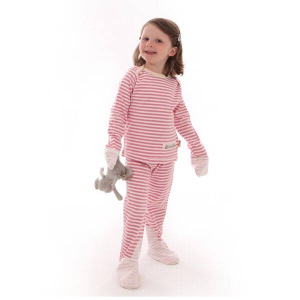 Little girl playing with teddy and wearing ScratchSleeves pink striped children's pyjama set. Shows the pyjama set is a loose, comfortable fit and children's hands can still be used naturally to play. Also shows that eczema clothing does not have to be boring.