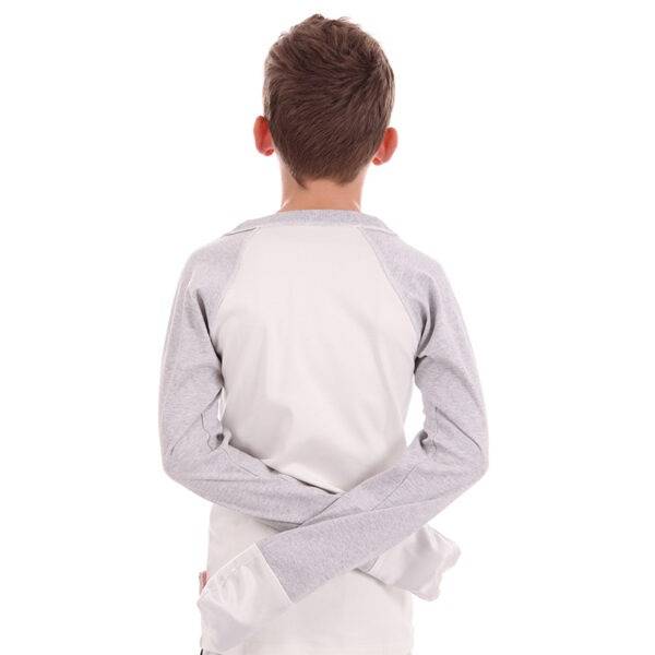 Teen boy wearing ScratchSleeves baseball style pyjama top with his hands behind his back showing the mitts. Pyjama top has external shoulder, neck and hem seams. White body and grey marl neck and sleeves, with white sewn in eczema mitts. 100% cotton body and 100% natural silk mitts.