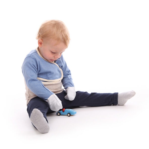 Little boy sat on floor playing with toy car, wearing t-shirt, trousers and children's bolero style blue marl cross-over ScratchSleeves. Shows that the ScratchSleeves are a comfortable fit, not restrictive and can be worn over clothing. Also shows that the cross-over front holds them firmly in place.