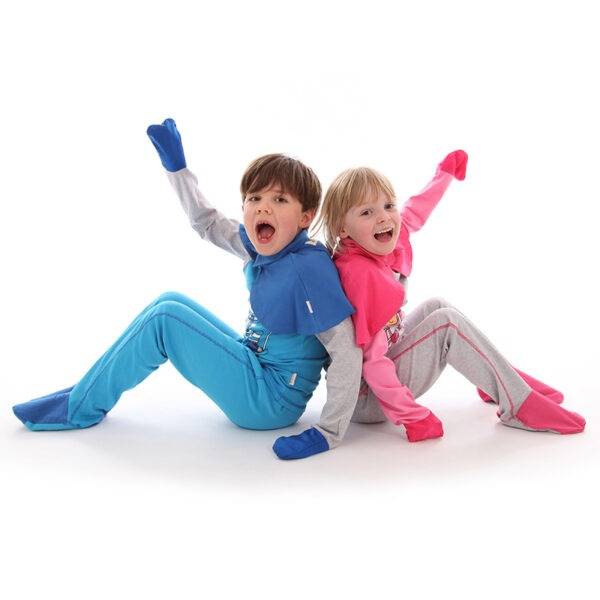 Young boy and girl sat on floor, having fun while wearing ScratchSleeves superhero pyjama sets with capes. Fun eczema pyjama sets with sewn in mitts and closed feet, in bright colours, with cool bear prints, showing eczema clothing does not have to be boring.