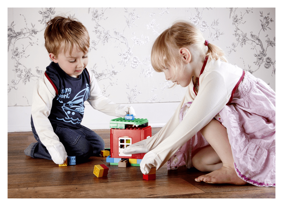 Two young children wearing ScratchSleeves playing with building blocks