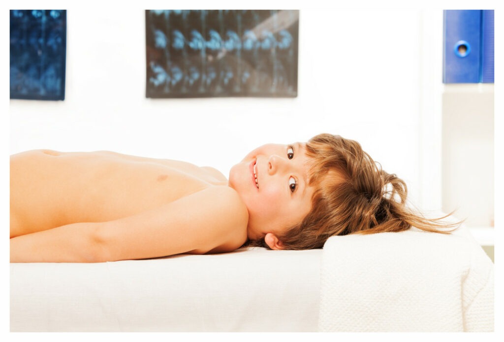 Smiling boy lying on acupressure treatment couch