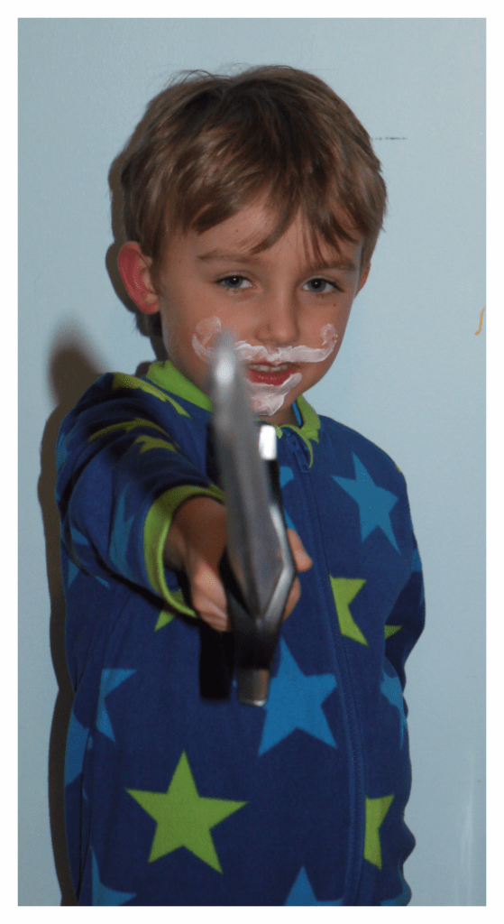 Young boy with curly moustache and pointed beard painted on with eczema emollient cream. He is brandishing a toy sword in the 'en guard' position. Definitely a fun bedtime routine!