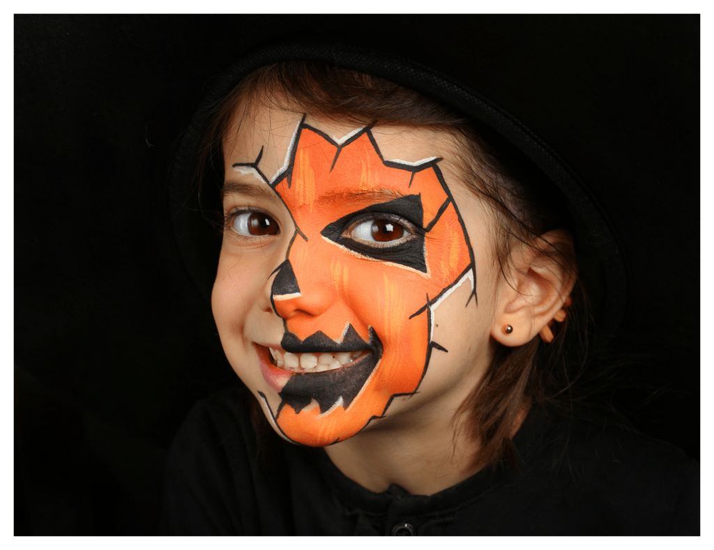 Girl with orange and black  Halloween face paint and a huge smile