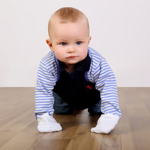 Little boy crawling on floor while wearing t-shirt, trousers and children's bolero style blue stripe ScratchSleeves. Shows that the ScratchSleeves are a comfortable fit, not restrictive and can be worn over clothing.