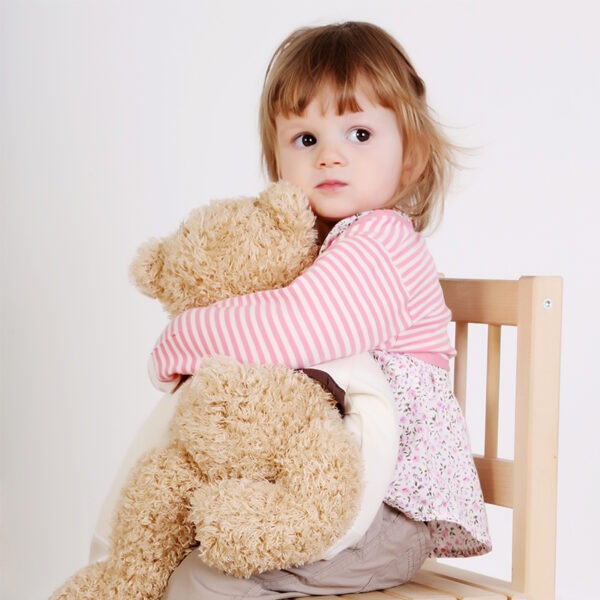 Little girl with teddy, wearing top, trousers and pink stripe ScratchSleeves. Shows that the ScratchSleeves are a comfortable fit, not restrictive and can be worn over clothing.