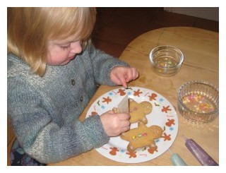 Young girl decorating gingerbread men with icing and mini smarties