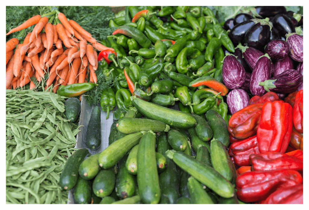 selection of colourful, flavonoid-rich fruit and vegetables on a market stall. Including carrots, beans, courgettes, peppers and aubergines.