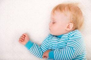 Older blonde baby sleeping in blue and white striped top