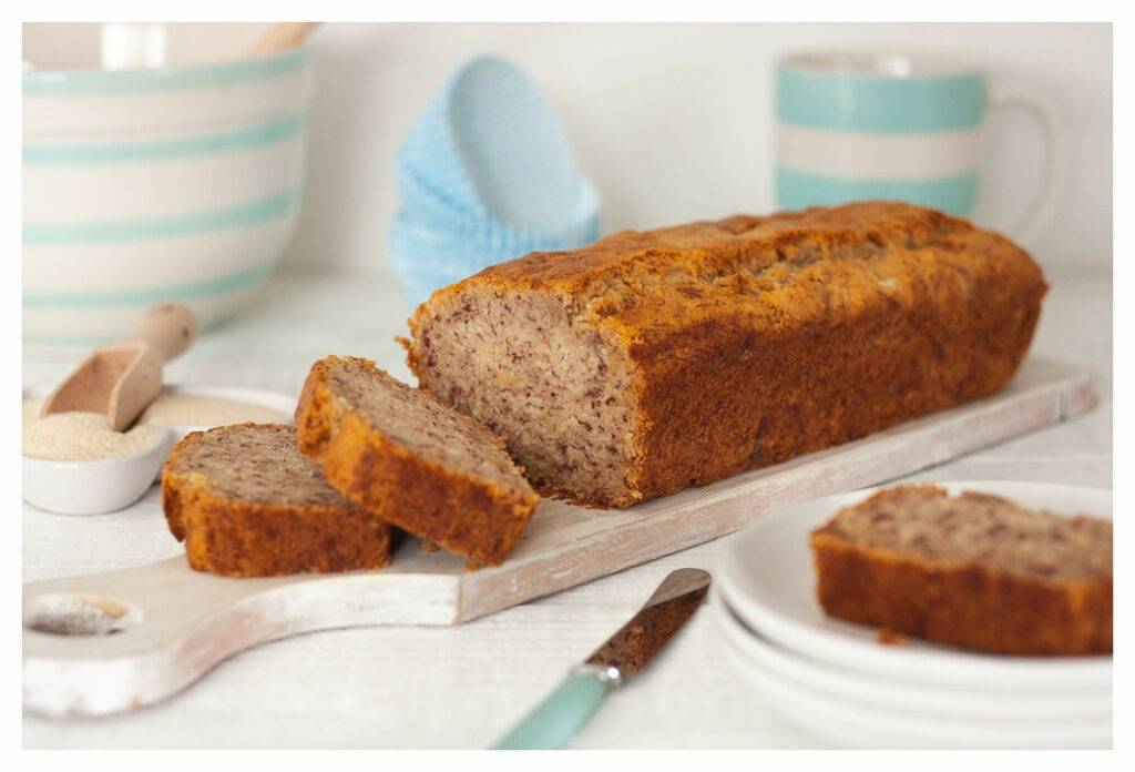 Eczema friendly moist banana bread, just out of the oven and sliced to show the heavy texture of the loaf. Served on white plates.