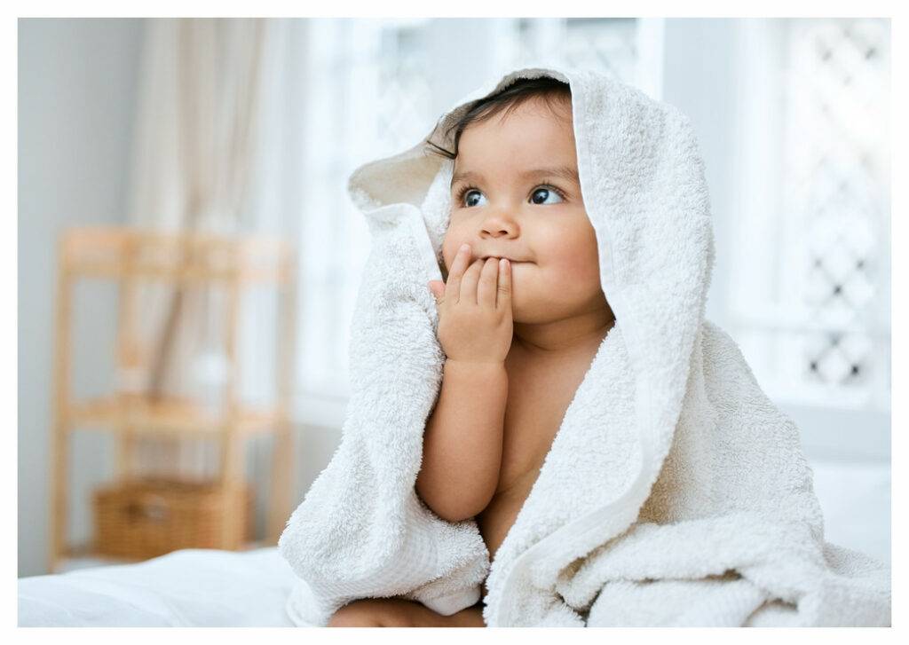 Toddler with big brown eyes wrapped in white towel following bath