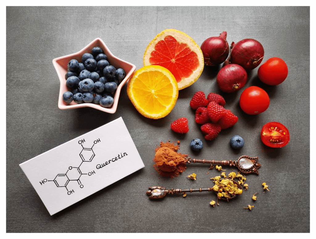 Colourful array of flavonoid rich fresh fruit and veg alongside a card with the chemical structure of quercetin, the flavonoid found in these foods., Including blueberries, red onions, tomatoes and citrus fruits (cut in half to show the segmentation pattern).