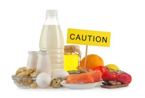 Selection of common food allergy triggers on while background including Milk, eggs, nuts, citrus fruits, fish and tomatoes