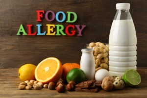 Selection of allergenic foods including milk, nuts, eggs and citrus fruits with Food Allergy in coloured letters