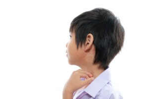 Young boy unconsciously scratching the eczema on his neck