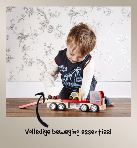 Kleine jongen speelt met een houten vrachtwagen terwijl hij ScratchSleeves draagt, wat laat zien hoe weinig deze eczeem-krabwanten de beweging en behendigheid beperken